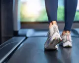 Nogi w butach sportowych biegnące po bieżni.