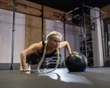 Kobieta wykonuje pompki z piłką w siłowni. Zastanawiasz się, crossfit jak często ćwiczyć, by osiągnąć takie rezultaty?